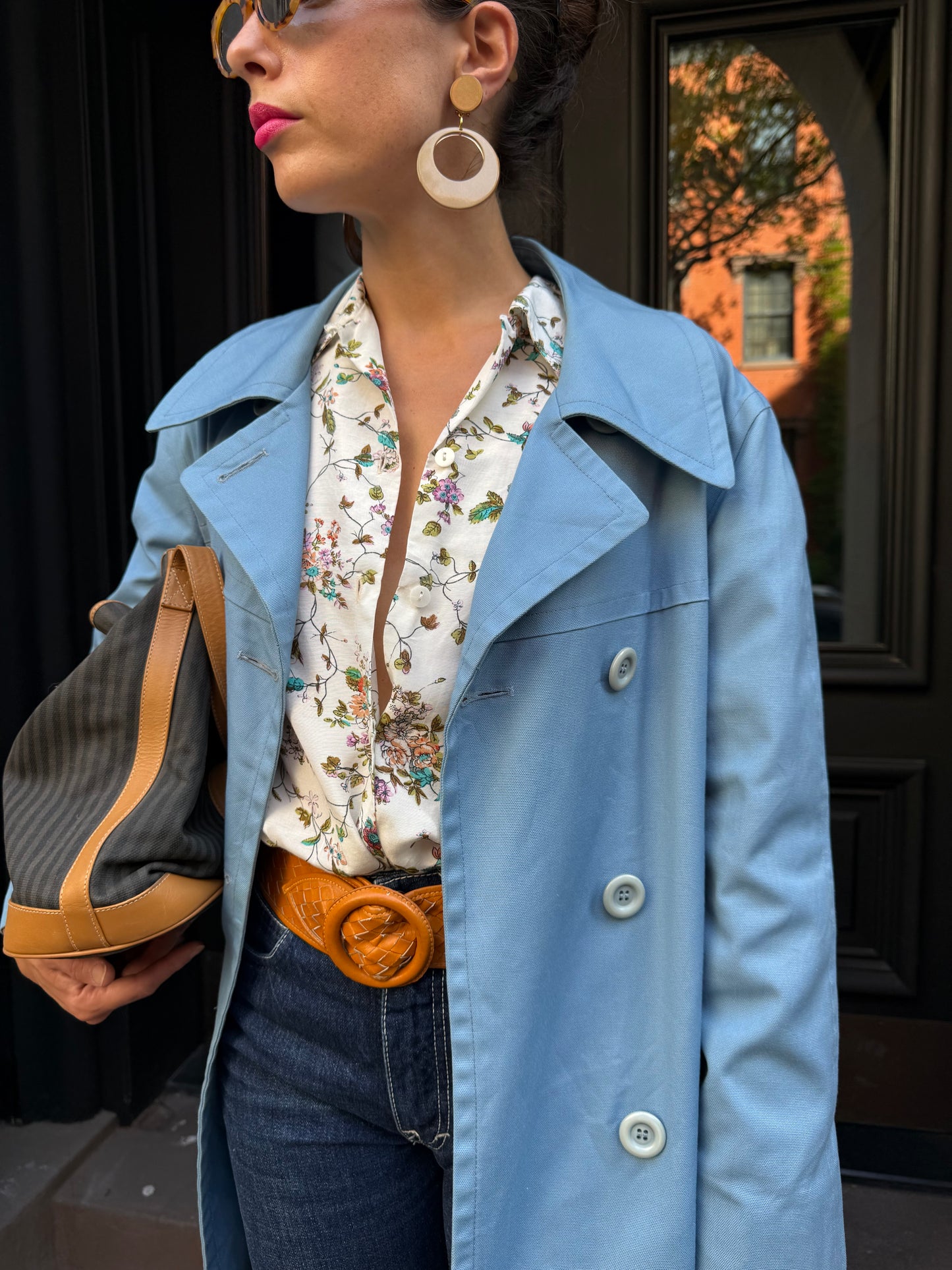Person wearing a light blue coat over a floral shirt with a blurred background